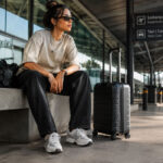 Mulher usando look streetwear confortável para viajar nas férias com tênis e bolsa de viagem